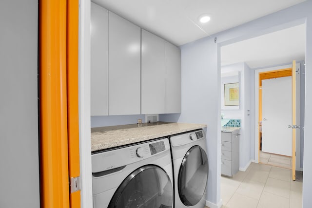 washroom with cabinets, washer and dryer, and light tile patterned floors