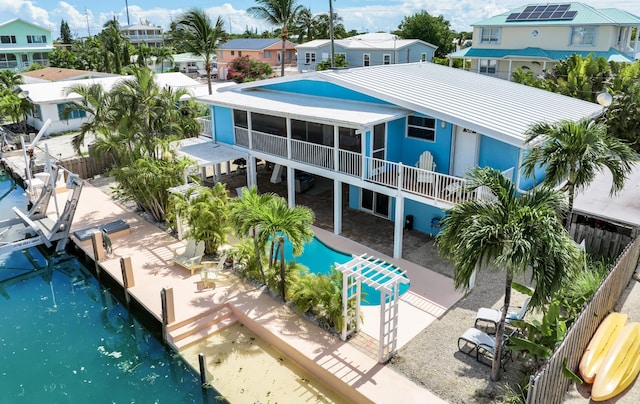 exterior space featuring a water view, a patio, a sunroom, and a fenced in pool