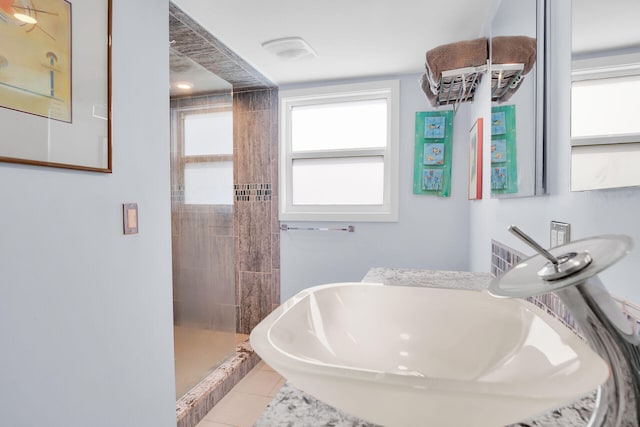 bathroom with tile patterned flooring, sink, and a tile shower