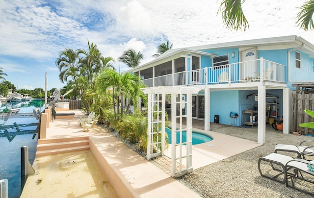 rear view of property featuring a water view, a sunroom, and a patio area