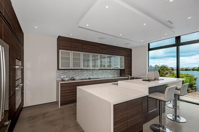 68 Mutiny Pl, Key Largo, FL 33037 - kitchen featuring a breakfast bar, a spacious island, expansive windows, black electric cooktop, and decorative backsplash