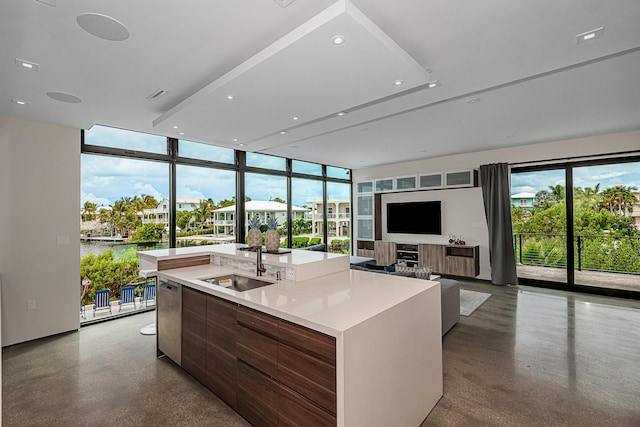 kitchen featuring sink, an island with sink, concrete floors, and a wealth of natural light