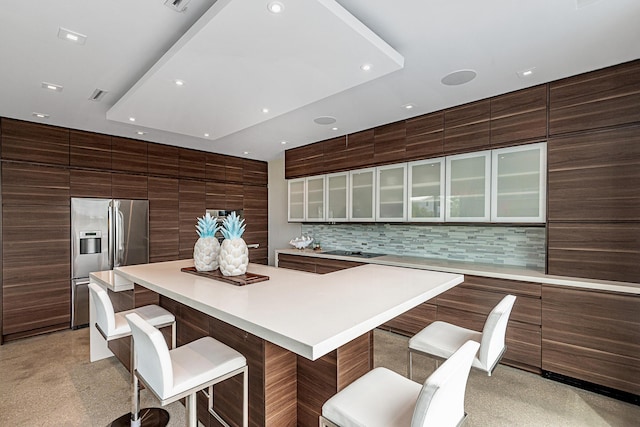 kitchen featuring stainless steel refrigerator with ice dispenser, a large island, backsplash, and a kitchen bar