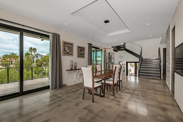 dining room with a tray ceiling and concrete floors