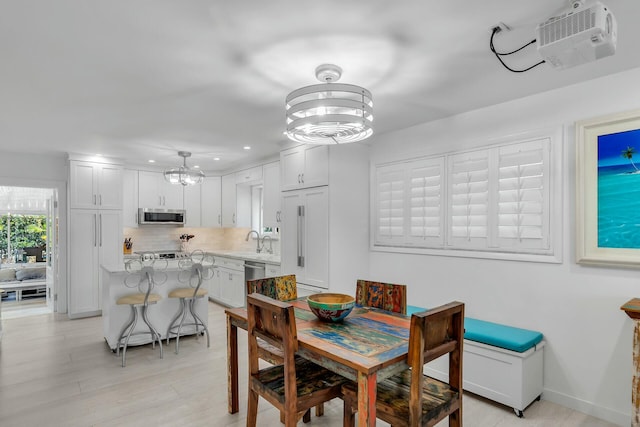 dining space with a chandelier, sink, and light hardwood / wood-style flooring