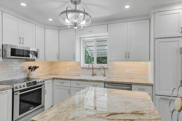 kitchen featuring white cabinetry, stainless steel appliances, decorative light fixtures, and sink