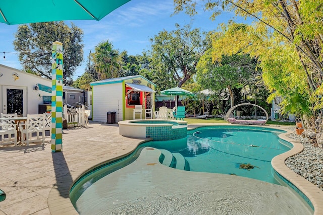 view of pool featuring an in ground hot tub, a patio, and a shed