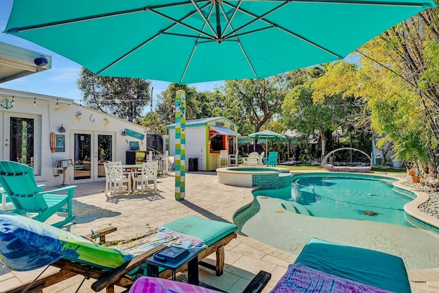 view of pool featuring an in ground hot tub, a patio, an outbuilding, and french doors