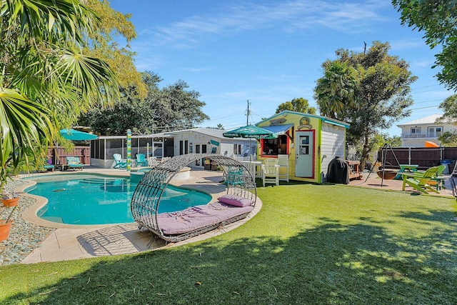 view of pool featuring an outbuilding, a lawn, and a patio