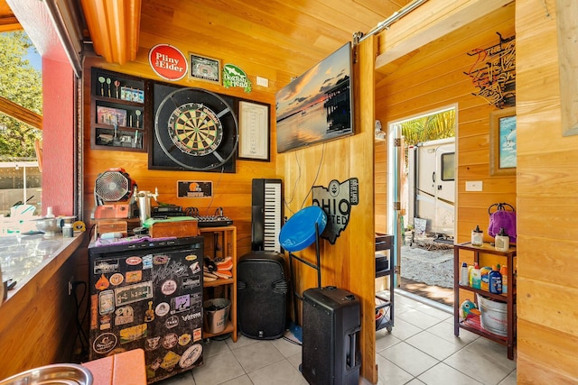 misc room featuring light tile patterned floors and wood walls