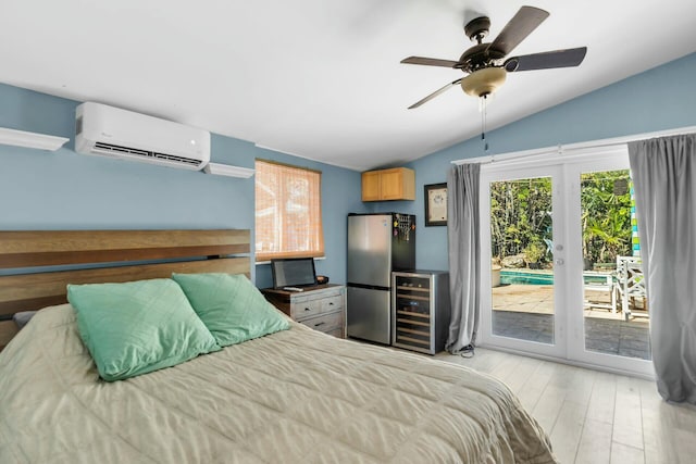 bedroom featuring a wall mounted air conditioner, stainless steel refrigerator, lofted ceiling, access to outside, and light hardwood / wood-style flooring