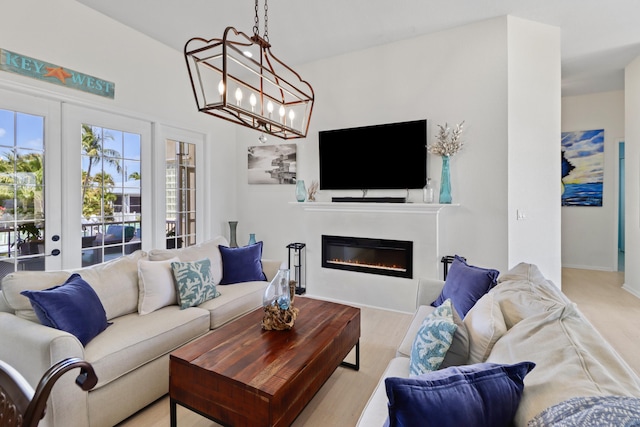living room with an inviting chandelier, baseboards, french doors, and a glass covered fireplace