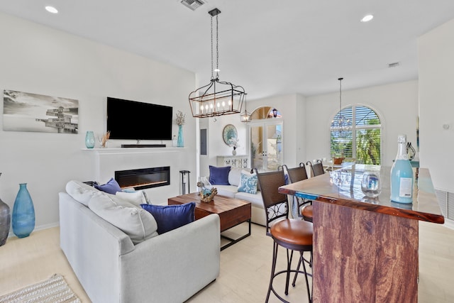 living room with visible vents, a glass covered fireplace, recessed lighting, and a chandelier