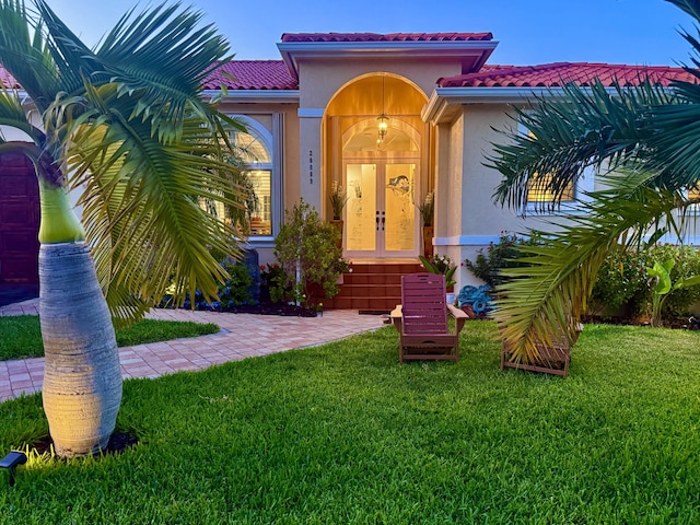 property entrance with a yard, a tile roof, and stucco siding