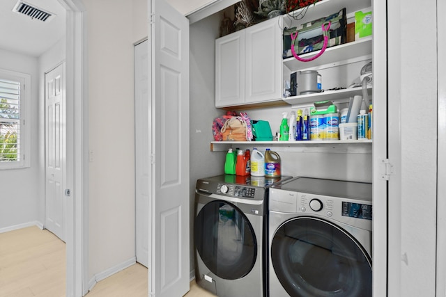 laundry room featuring cabinet space, light wood-type flooring, visible vents, washing machine and clothes dryer, and baseboards