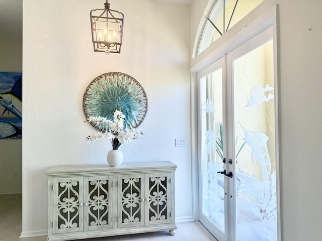 foyer entrance with a chandelier, french doors, and baseboards