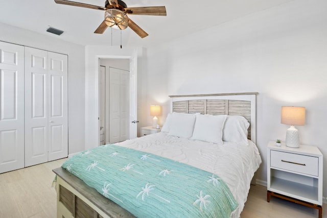 bedroom with a closet, visible vents, wood finished floors, and ceiling fan