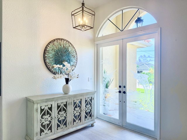 entryway with wood finished floors, french doors, a healthy amount of sunlight, and a notable chandelier