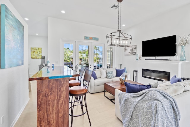 living room featuring french doors, visible vents, a glass covered fireplace, light wood-style floors, and recessed lighting