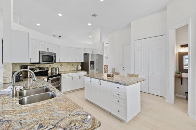 kitchen featuring a center island, visible vents, a sink, backsplash, and appliances with stainless steel finishes