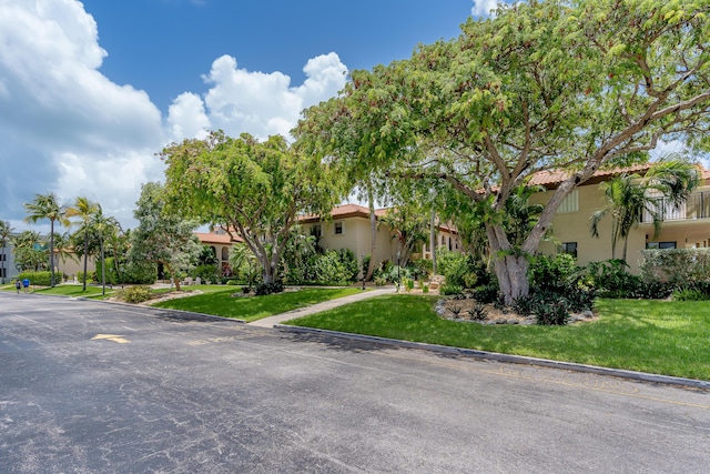 view of front facade featuring a front yard, a tile roof, and stucco siding