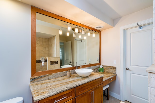 bathroom with visible vents, toilet, vanity, tiled shower, and a tile fireplace