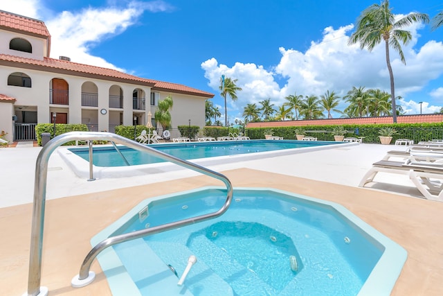 community pool featuring a patio area, fence, and a community hot tub