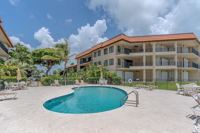 community pool with fence and a patio
