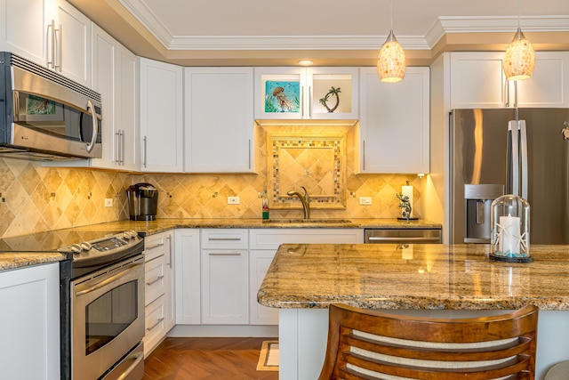 kitchen with stainless steel appliances, white cabinets, a kitchen bar, and a sink