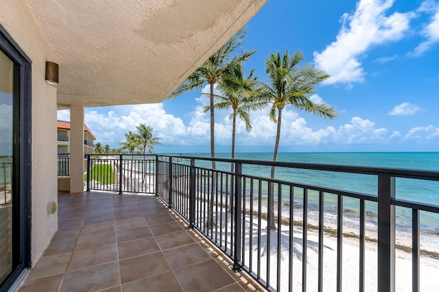 balcony featuring a view of the beach and a water view