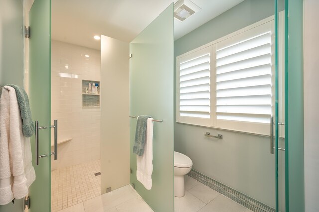 bathroom featuring tile patterned flooring, a shower with door, and toilet