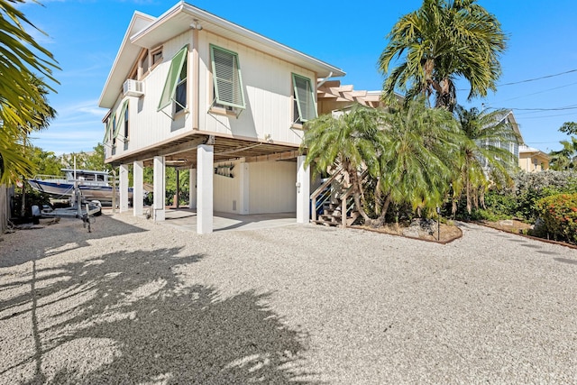 view of side of home with stairs, a carport, and a wall mounted AC