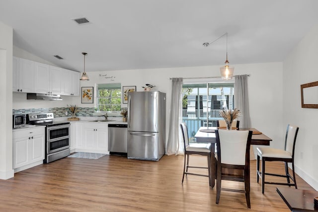 878 La Paloma Rd, Key Largo, FL 33037 - kitchen featuring stainless steel appliances, under cabinet range hood, light wood-style floors, white cabinets, and vaulted ceiling