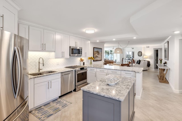 kitchen with sink, appliances with stainless steel finishes, white cabinetry, backsplash, and light stone countertops