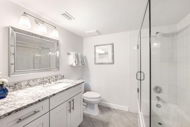 full bathroom featuring vanity, enclosed tub / shower combo, and toilet