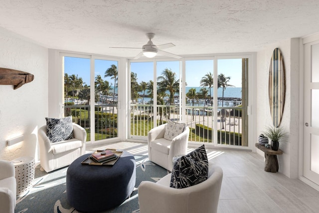 sunroom / solarium featuring a water view and ceiling fan