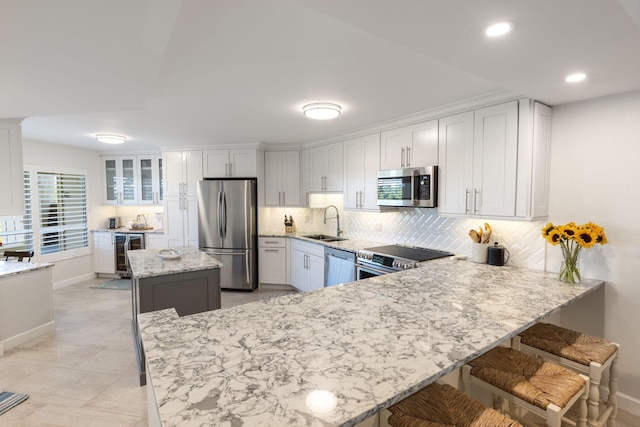 kitchen featuring stainless steel appliances, beverage cooler, sink, and white cabinets