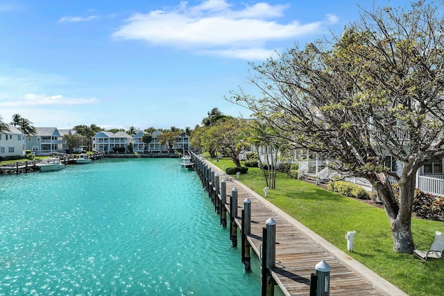 dock area with a residential view, a lawn, and a water view