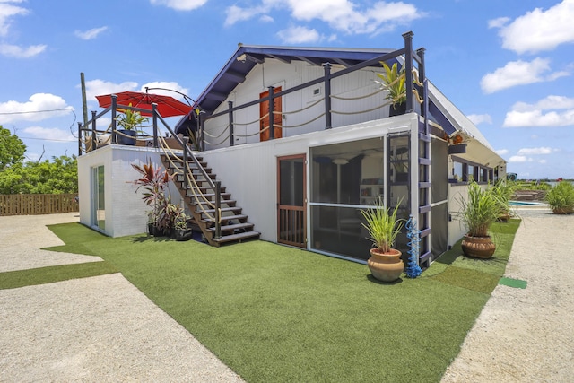 back of property with a yard and a sunroom