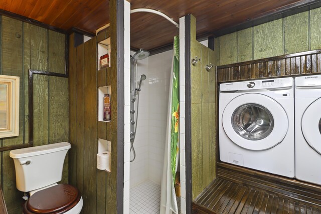 clothes washing area featuring washing machine and dryer, wooden ceiling, and wooden walls