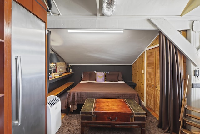 carpeted bedroom with lofted ceiling and stainless steel fridge