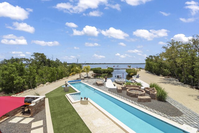 view of swimming pool featuring a water view, an outdoor fire pit, and a patio area