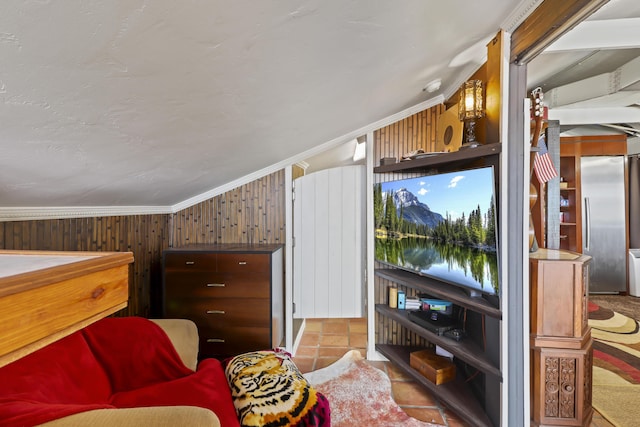 interior space featuring ornamental molding, stainless steel fridge, vaulted ceiling, and wood walls