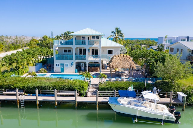 back of property featuring a fenced in pool, a water view, metal roof, and a balcony