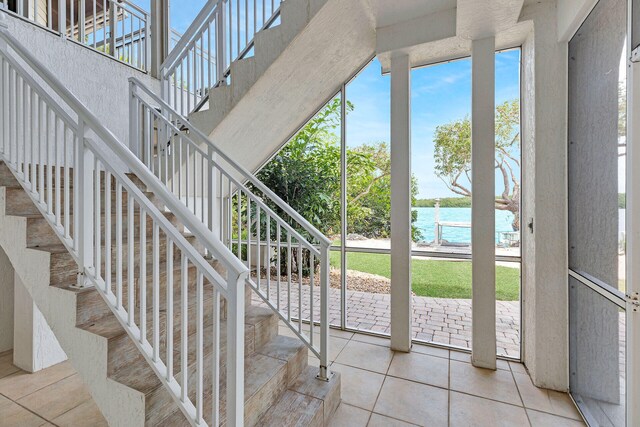 staircase with a water view, a towering ceiling, and tile patterned floors