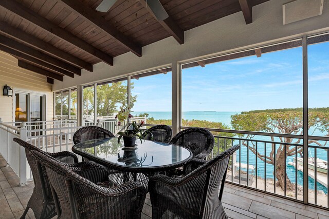 sunroom / solarium with vaulted ceiling with beams, wooden ceiling, a beach view, and a water view