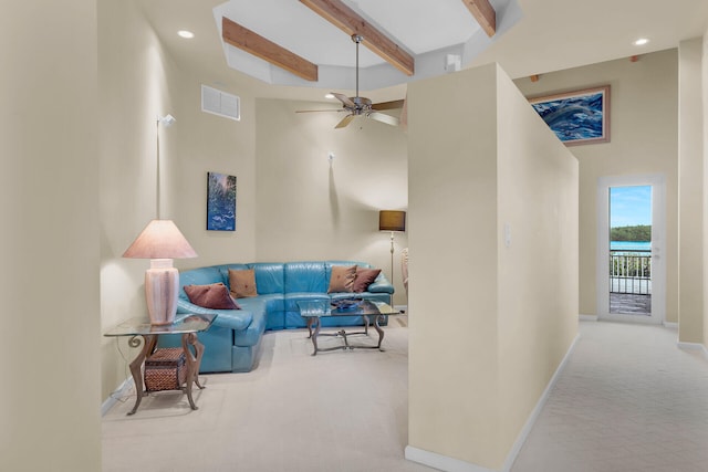 carpeted living room featuring ceiling fan, a towering ceiling, and beam ceiling