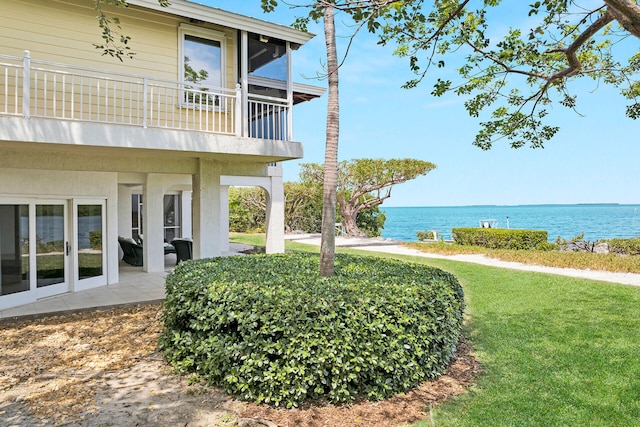 view of yard featuring a water view, a balcony, and a patio