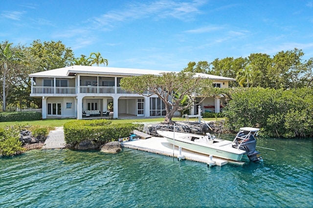 rear view of house featuring a water view, a patio area, and a sunroom