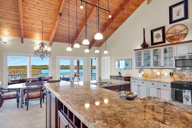 kitchen with white cabinetry, hanging light fixtures, appliances with stainless steel finishes, and a water view